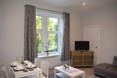a living room with a table and a window at Kelpies Serviced Apartments- Victoria in Falkirk