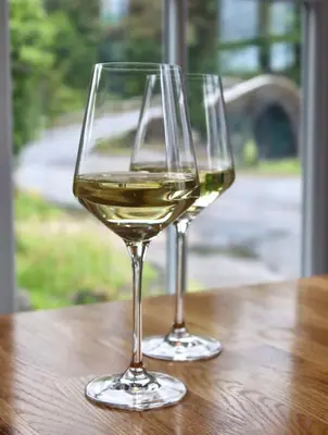 two glasses of white wine sitting on a wooden table at Tigh an Truish Inn in Oban