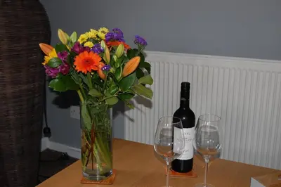 a vase of flowers and two wine glasses on a table at Creag Mhor Self Catering Holiday Apartment in Aberfoyle