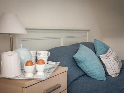 a bed with a tray with eggs on a night stand at The Grooms Cottage in Mauchline