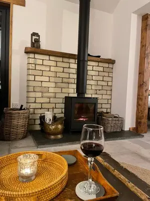 a glass of wine sitting on a table in front of a fireplace at Blair Cottage in Rowardennan