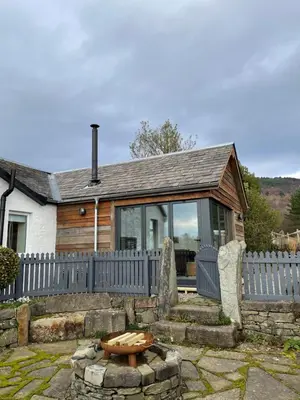 a house with a fence and a bench in the yard at Blair Cottage in Rowardennan