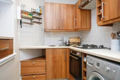 a kitchen with wooden cabinets and a dishwasher at Walkable 1BR Near Castle, Grassmarket, Food in Edinburgh