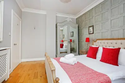 a bedroom with a large white bed with red pillows at Walkable 1BR Near Castle, Grassmarket, Food in Edinburgh