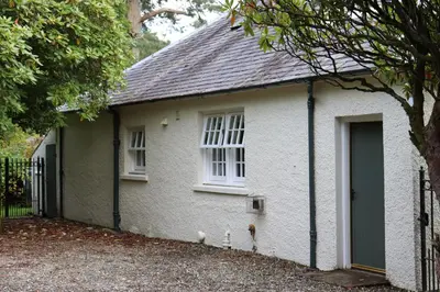 a white house with two cats standing outside of it at Farmston Lodge in Callander