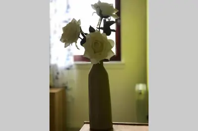a black vase with white flowers in it at Chic 2 Bed Apartment with Free Parking- Recently Redecorated, 10 Minutes to City Centre in Edinburgh