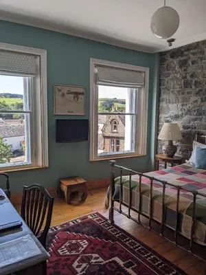 a bedroom with a bed and two windows at Kirkview House in Moffat