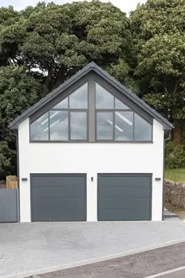 a white garage with two garage doors and windows at 1 Bed Studio - Sleeps 4 - Parking - Wifi in Saint Davids