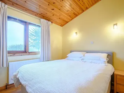 a bedroom with a white bed with a wooden ceiling at Ard Cuan in Torbeg