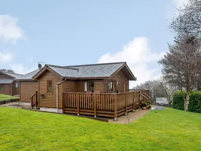 a log house with a deck and a yard at Ard Cuan in Torbeg