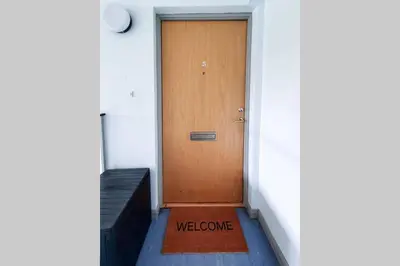 a wooden door with a welcome mat in front of it at Hilton Wynd Apartment in Rosyth