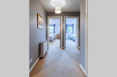 a hallway with a door leading to a room with two beds at Hilton Wynd Apartment in Rosyth