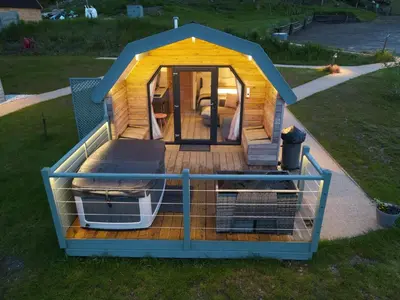 a large wooden house with a cage in the grass at Bonnie Barns - Adults Only Luxury Lodges with hot tubs in Luss