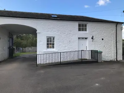a white brick building with a gate in front of it at DairyCottage, 5, TELFORD MEWS BEATTOCK in Moffat