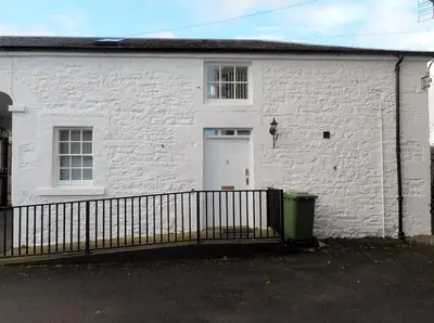 a white building with a white door and a fence at DairyCottage, 5, TELFORD MEWS BEATTOCK in Moffat