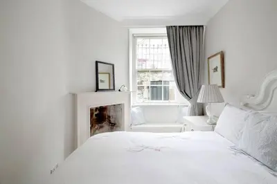a white bedroom with a white bed and a fireplace at Hamilton Place - Beautiful and central city apartment with private entrance sleeps 4 in Edinburgh