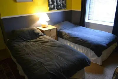 two beds in a bedroom with a lamp on a night stand at North Lodge Kilmun in Kilmun