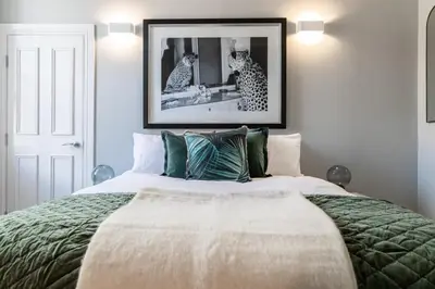 a bedroom with a large bed and a picture on the wall at Beautiful 4 bed flat in perfect central location in Glasgow