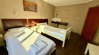 a hotel room with two beds and a table at Lomond Park Hotel in Balloch