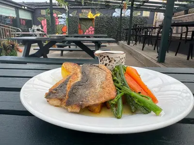 a white plate with meat and vegetables on a table at Lomond Park Hotel in Balloch