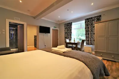 a bedroom with a bed and a table and a window at Signature - Linden Cottage Room 1 in Airdrie