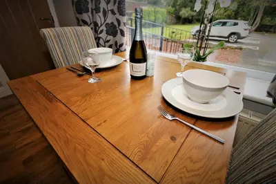 a wooden table with a bottle of wine and glasses at Signature - Linden Cottage Room 1 in Airdrie