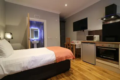 a bedroom with a bed and a kitchen and a table at Signature - Linden Cottage Room 2 in Airdrie