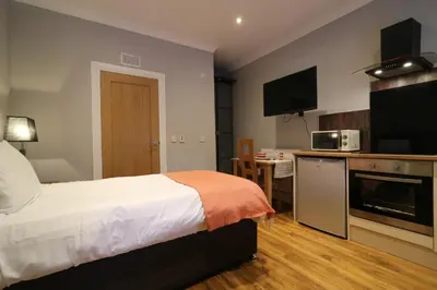 a hotel room with a bed and a kitchen at Signature - Linden Cottage Room 2 in Airdrie