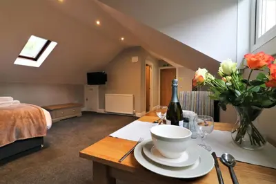 a room with a table with a bottle of wine and flowers at Signature - Linden Cottage Room 3 in Airdrie