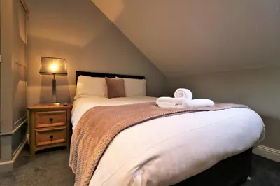 a bedroom with a bed with two towels on it at Signature - Linden Cottage Room 3 in Airdrie