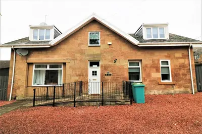 a brick house with a white door and a fence at Signature - Linden Cottage Room 4 in Airdrie