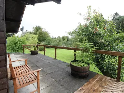 a patio with two benches and a wooden fence at Millmore Cabin in Killin