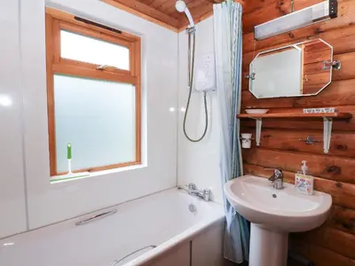 a bathroom with a sink and a toilet and a window at Millmore Cabin in Killin