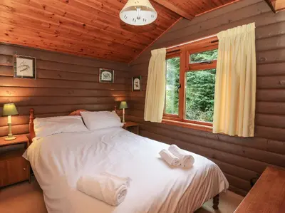 a bedroom with a bed in a log cabin at Millmore Cabin in Killin