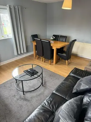 a living room with a couch and a table and chairs at Kelpies Serviced Apartments- Campbell in Pumpherston