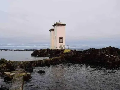 a lighthouse on a rocky island in the water at Upper Imeraval Cottage Sleeps 6 Pet-Friendly in Port Ellen