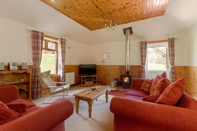 a living room with two red couches and a fireplace at Doonans Cottage in Maybole
