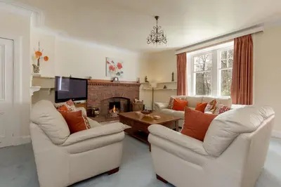 a living room with two chairs and a fireplace at Balcraig House in Maybole