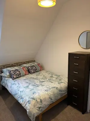 a bedroom with a bed with a dresser and a mirror at Eilean View in Lamlash