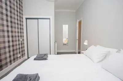 a bedroom with a large white bed and a window at The Warwick Apartment in Greenock