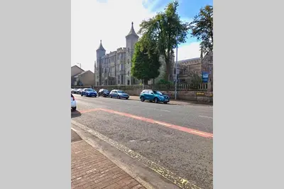 a street with cars parked on the side of the road at The Warwick Apartment in Greenock