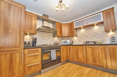 a kitchen with wooden cabinets and a stove top oven at Edinburgh Pearl Apartments - Fountainbridge Residence in Edinburgh