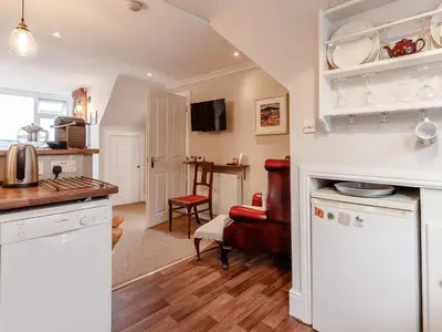 a kitchen with white cabinets and a red chair at Forth Reflections in Queensferry