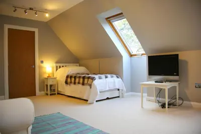 a bedroom with a bed and a flat screen tv at Pirn Mill Self Catering Cottage in Cladich