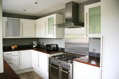 a kitchen with white cabinets and a stove top oven at Pirn Mill Self Catering Cottage in Cladich