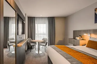 a hotel room with a bed and a table and chairs at Maldron Hotel Glasgow City in Glasgow