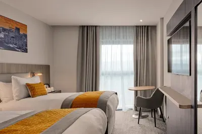 a hotel room with two beds and a desk at Maldron Hotel Glasgow City in Glasgow