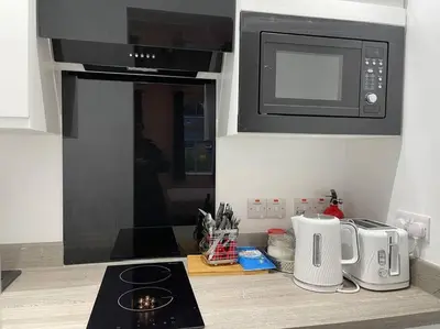a kitchen with a stove top oven and a microwave at Premier Studio B in Broxburn