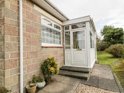 a front door of a brick house with potted plants at Honesty Cottage in Girvan