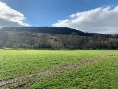 a large green field with a hill in the background at The Clachan Flat in Rosneath